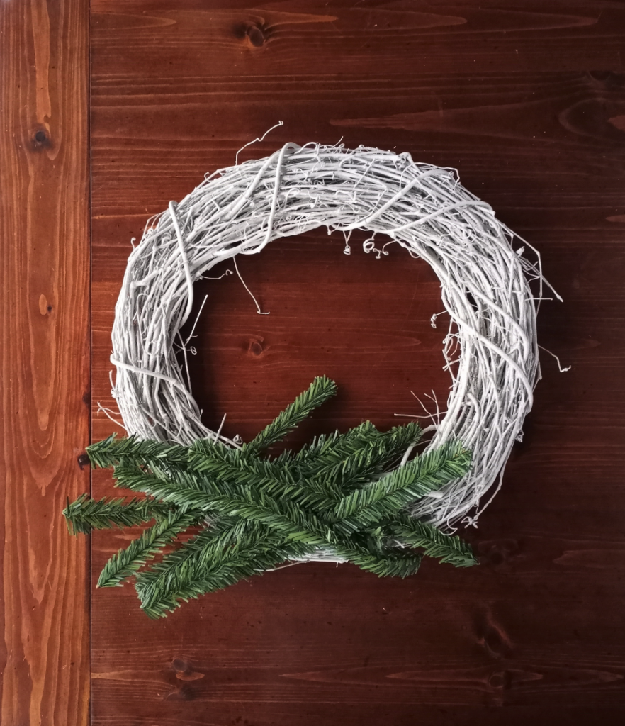 Step 3 in making a grapevine bottle brush wreath, the wreath with greenery.