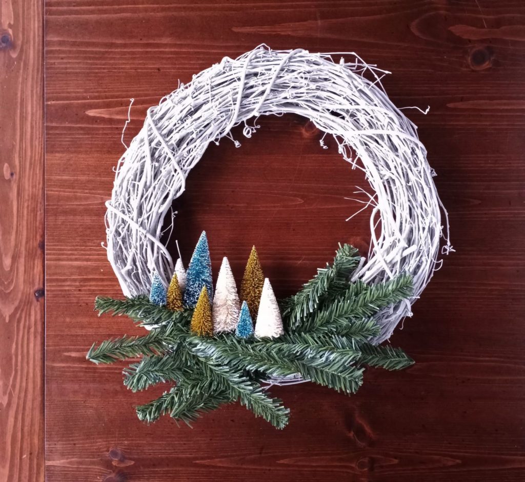 Step 5 in making a grapevine bottle brush wreath, the wreath with greenery and bottle brush trees.